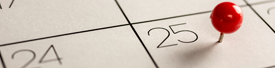 A red pushpin on the number 25 of a calendar, marking a specific date.