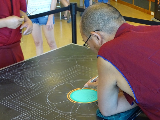 The outline of Green Tara is hand drawn into the first layer of green sand with a needle-like instrument.