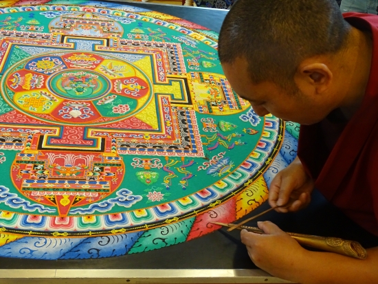 As the mandala neared completion, the monks painted two last two circles of detail surrounding the lotus petals. First a circle of thunderbolds, known as the wall of vajra (or dorje in Tibetan), a dome of outer protection and impenetrable force. The outside is a ring of fire symbolizing wisdom.