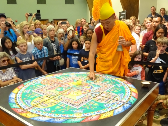 Rinpoche rings the bell and draws directional lines to the heart of the mandala.