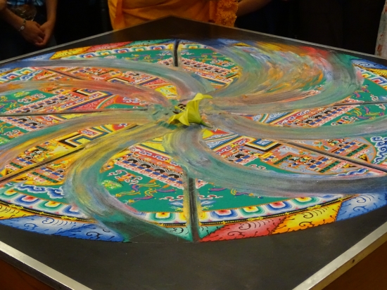 The swish of a paint brush blends the mandala's colorful sands like a pinwheel.