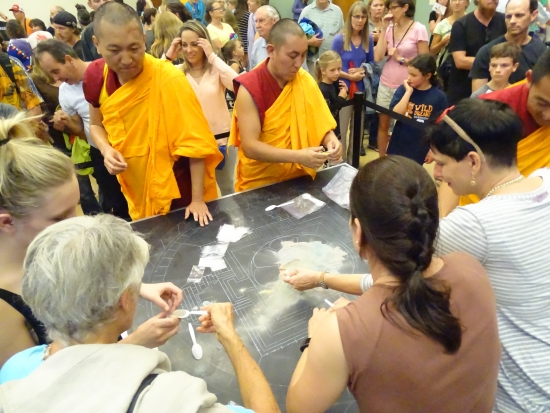 Volunteers help the monks disperse to the community part of the sand that they did not put in an urn for the trip to the Yampa River.